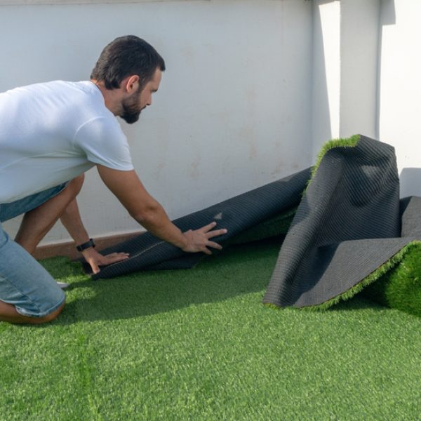 man installing artificial synthetic grass on terrace